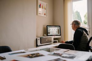 Elderly man engaged in photo editing at home office, showcasing a cozy and focused workspace.